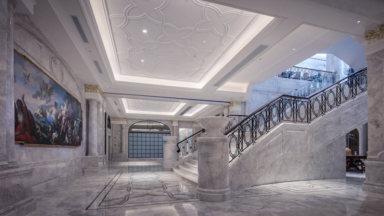 creative-02 Elegant marble hallway featuring a grand staircase and ornate ceiling design.