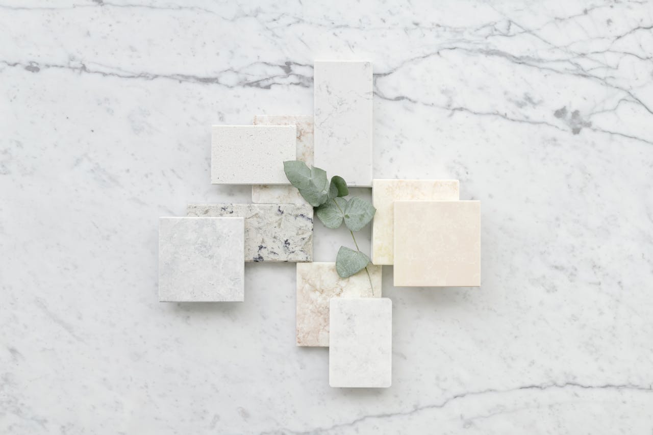 brand-01 Elegant arrangement of marble tiles with eucalyptus leaves on a marble background.