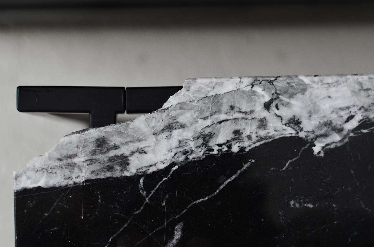 Top view of aged table with damaged marble surface on floor in house room in daylight